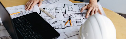 table filled with floor plans, laptop and other engineering things