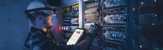 Electrical engineer wearing goggles and hardhat working on servers 