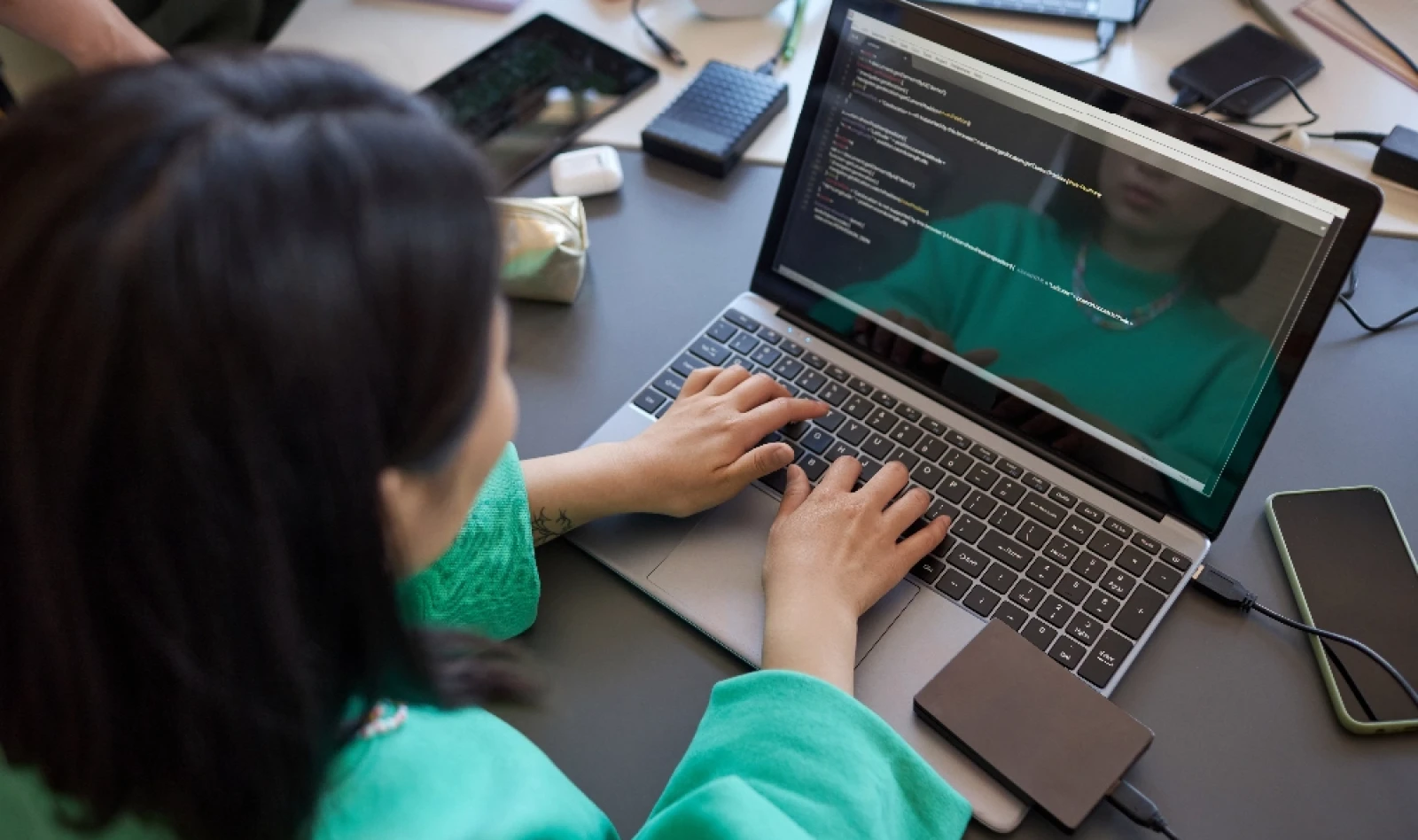 Focus on the hands of a young female student, typing on a laptop keyboard while analyzing and decoding data on screen