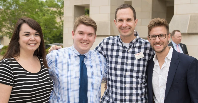 Group of four smiling Bradley University students outdoors on campus