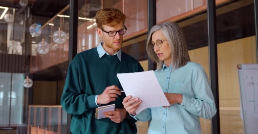 Man and woman in office setting looking over a documents