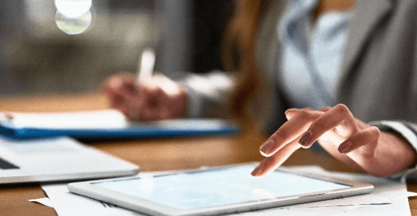 Hands of woman working on tablet and taking notes